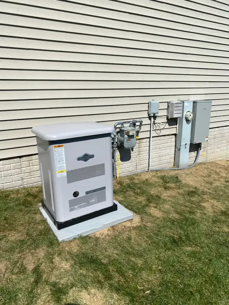 Outdoor standby generator on a concrete pad beside a house, connected to gas line and electrical meters.